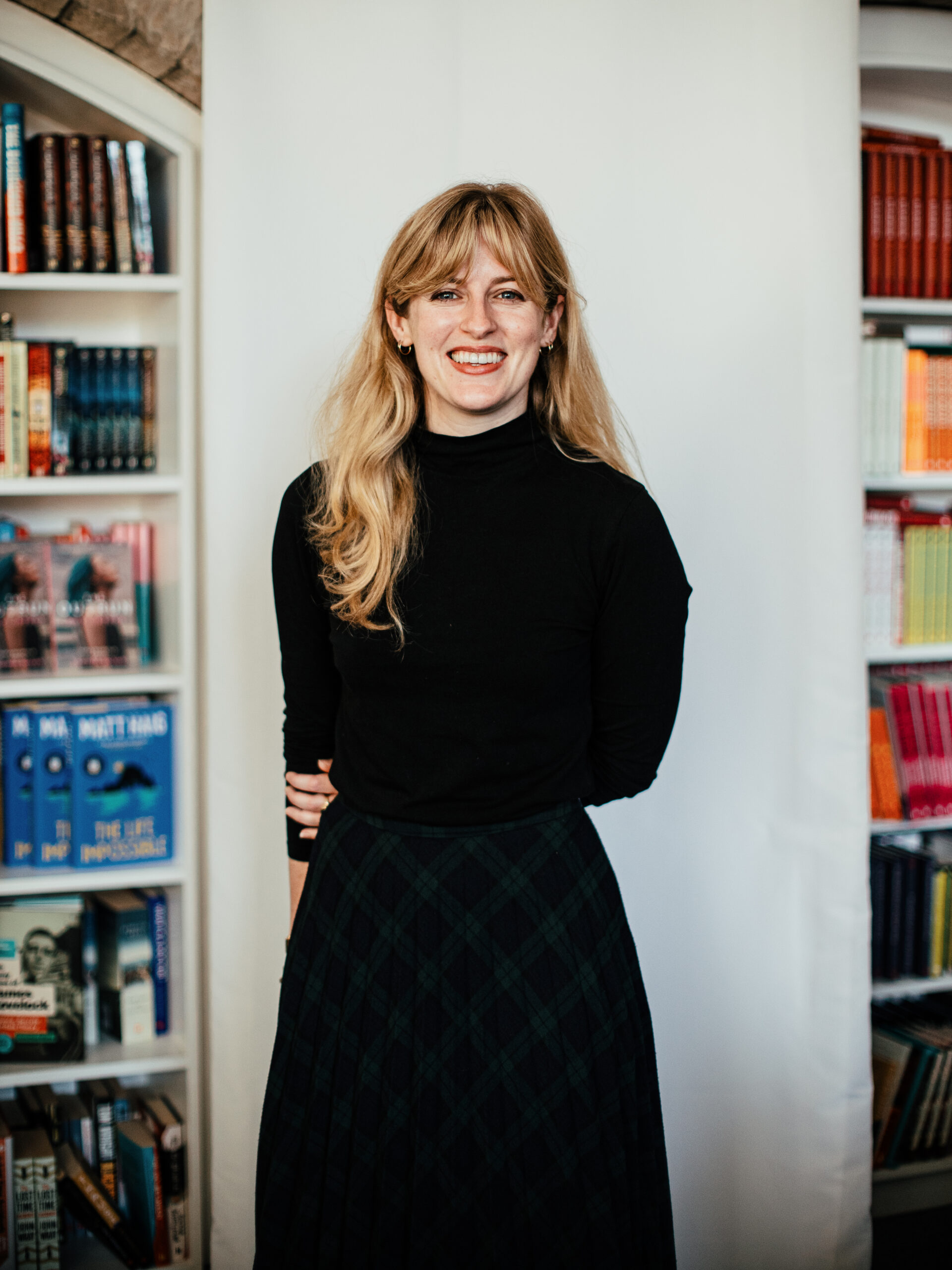 Rebecca Scott photographed in front of a plain background and some books